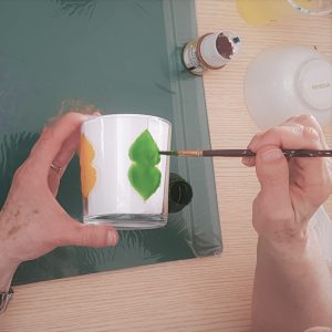 des mains qui peignent un verre au pinceau fin